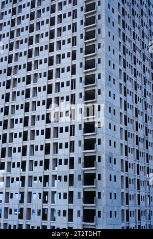 Un bâtiment inachevé se dresse devant un ciel gris sombre, dépourvu de tout signe de vie ou d'activité, avec ses espaces vides qui attendent d'être remplis Banque D'Images