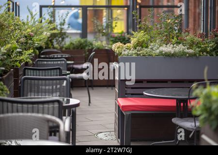 Café de rue vide de style européen moderne avec de belles fleurs naturelles près des tables en journée ensoleillée. Banque D'Images