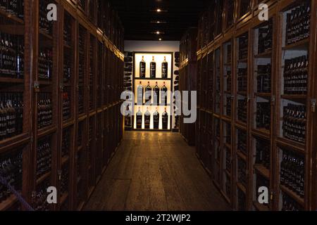 Intérieur de cave à vin avec des bouteilles de vin sur des étagères dans une rangée dans la cour, ville de Funchal sur l'île de Madère, Portugal Banque D'Images