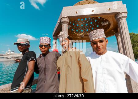 Joyeux local les jeunes hommes en vêtements traditionnels et occidentaux sourient pour la caméra à Mutrah Muscat à Oman Banque D'Images