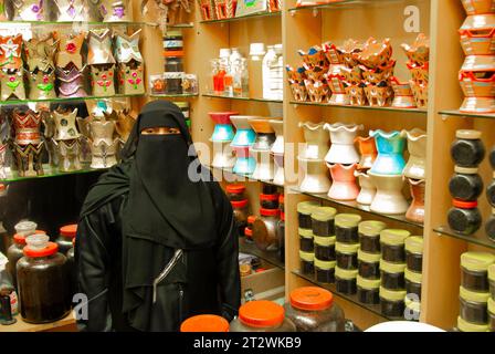 Une femme portant des vêtements traditionnels complets vend des produits dans un petit magasin à Salalah, dans le sud d'Oman Banque D'Images