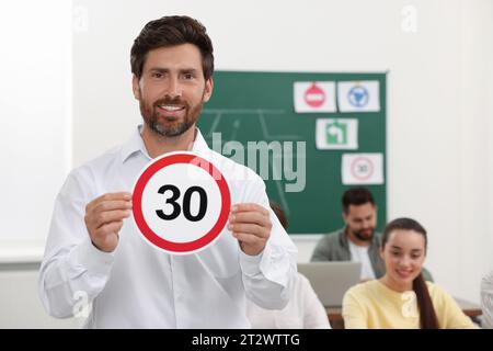 Enseignant montrant le panneau de limite de vitesse pendant la leçon en auto-école. Espace pour le texte Banque D'Images