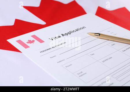 Immigration au Canada. Formulaire de demande de visa et stylo sur drapeau, closeup Banque D'Images