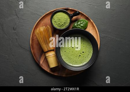 Tasse de thé matcha frais, fouet en bambou et poudre verte sur table noire, vue de dessus Banque D'Images