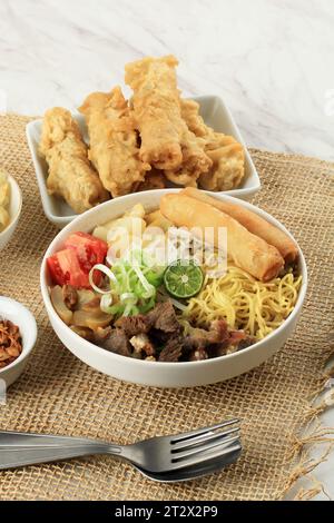 Soto Mie Bogor ou soupe de nouilles au bœuf, servi avec nouilles, vermicelles, chou, tomate, et Rice Noodle Spring Roll. Banque D'Images