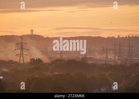 Londres , Royaume-Uni 22 octobre 2023. Les tours de transmission de l'électricité à Wimbledon, au sud-ouest de Londres, se profilent contre un ciel orange vif au lever du soleil un jour après la pluie torrentielle de l'orage Babet .Credit amer ghazzal/Alamy Live News Banque D'Images