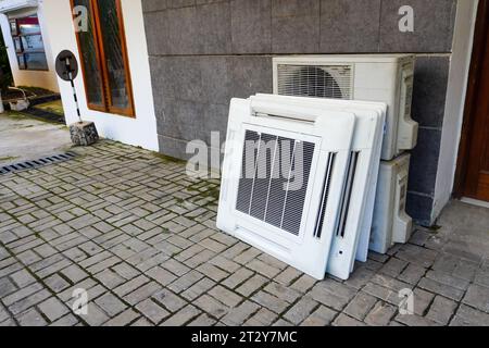 Affichage d'une pile de ventilateurs CA défectueux et d'unités CA suspendues dysfonctionnelles stockées sur le sol, indiquant leur élimination imminente Banque D'Images