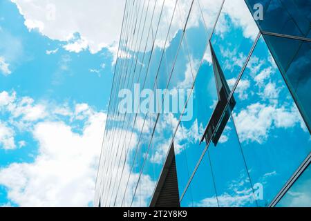 Fenêtre vitrée ouverte dans un bâtiment à plusieurs étages reflétant le ciel bleu nuageux enchanteur Banque D'Images