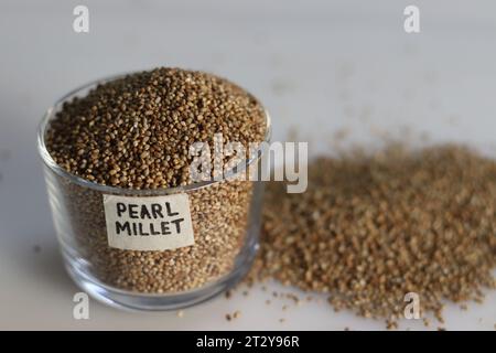 Grains de millet perlé dans un bol en verre avec étiquette dessus rempli à bord, mettant en valeur leur perle comme beauté naturelle et nutrition saine. Idéal pour f Banque D'Images