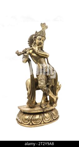 statue dorée du seigneur krishna confectionnée avec des détails, un avatar de vishnu, jouant de la musique de flûte près d'une vache dans une position de danse, isolée Banque D'Images