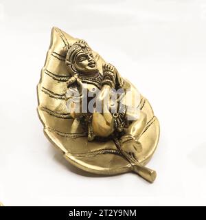 dieu hindou seigneur bébé krishna sur une statue de feuille fabriquée en détail sur métal doré brillant isolé Banque D'Images