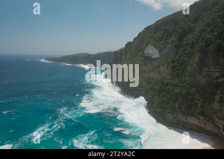 Profitez de la tranquillité du rivage turquoise et des eaux mousseuses de Nusa Penida, comme en témoigne la grandeur d'une chaîne de falaises. Banque D'Images