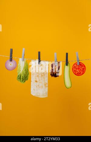 Shawarma ingrédients suspendus au fil dans l'air : viande de boeuf, laitue, oignon, tomates, fromage Banque D'Images