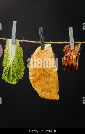 Doner kebab ingrédients accrochés au fil dans l'air : viande de boeuf, laitue, oignon, tomates, fromage Banque D'Images