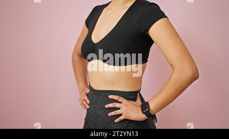 Jeune belle femme hispanique portant des vêtements de sport debout sur fond rose isolé Banque D'Images