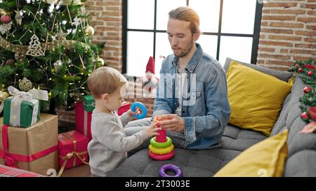 Père et fils célébrant noël en jouant avec des jouets à la maison Banque D'Images