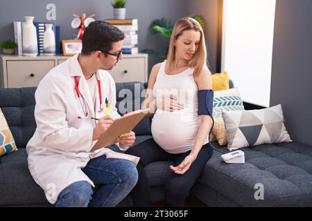 Homme et femme médecin et patiente enceinte ayant une consultation médicale en utilisant le tensiomètre à la maison Banque D'Images