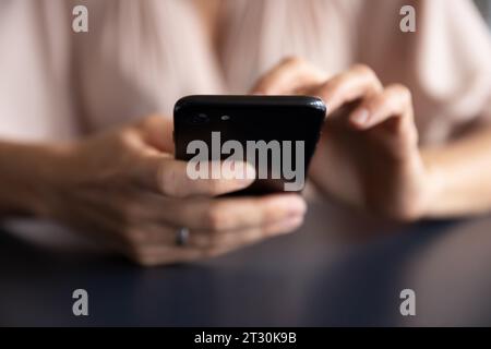 Gros plan mains féminines tenant le smartphone noir Banque D'Images