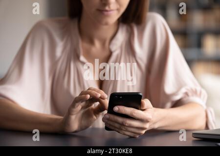 Gros plan Focus mains féminines tenant smartphone noir ayant du plaisir en ligne Banque D'Images