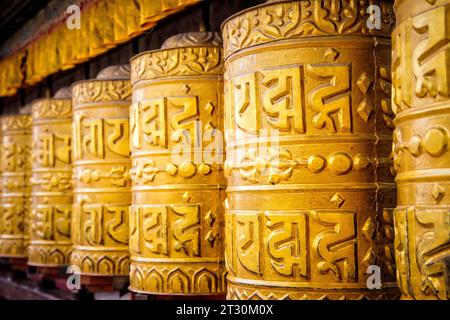 Des roues de prière dorées se tiennent prêtes au temple du singe à Katmandou, au Népal. Banque D'Images