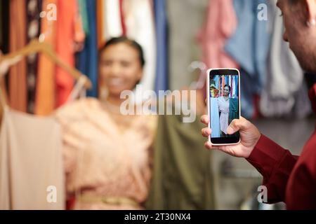 Jeune homme prenant la photo d'un ami avec des robes pour son blog de mode Banque D'Images