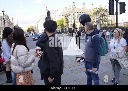 Un couple nouvellement marié pose pour une photo de mariage au soleil à Westminster, au centre de Londres. Deux avertissements de graves inondations sont en place autour de la rivière Idle, près de Retford dans le Nottinghamshire, ce qui signifie un risque de mort ou de blessures graves, car le niveau de l'eau continue d'augmenter. Date de la photo : dimanche 22 octobre 2023. Banque D'Images