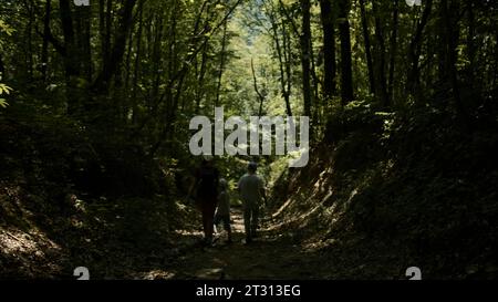 Touristes travail d'équipe, randonnée familiale heureuse dans l'escalade de forêt. Créatif. Vue arrière d'une mère avec des garçons marchant à travers les jungles Banque D'Images