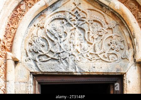 Goght, Arménie - 30 septembre 2023 : Portail sculpté au-dessus de l'entrée de l'église dans le monastère de Geghard dans la haute vallée de l'Azat le jour ensoleillé de l'automne. Geghard i Banque D'Images