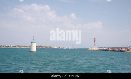 Port maritime, port et phare sur un fond de ciel nuageux bleu. Action. Bateaux de croisière et bateaux de ferry en mer Méditerranée. Banque D'Images