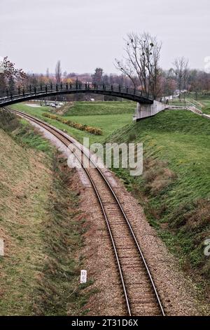 Petite passerelle au-dessus de la voie ferrée lors d'une journée d'automne nuageux. Rails près de la ville polonaise de Zamosc. Banque D'Images