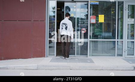 Serbie, Belgrade - 20 juin 2023 : un homme entre dans le magasin avec une porte automatique. Clip. L'homme s'arrête à la porte automatique du magasin. Le jeune homme attendait l'ouverture Banque D'Images