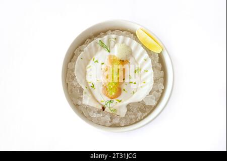 Noix de Saint-Jacques en sauce avec caviar de poisson volant sur une coquille sur glace isolée. Photo de haute qualité Banque D'Images