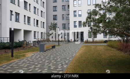 Cour d'un complexe résidentiel moderne. Film. Route avec banc à l'entrée de la maison moderne à plusieurs étages. Belle cour avec banc et Banque D'Images