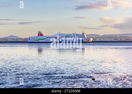 Le bateau ferry 'Stena Line' 'Stena Adventurer' navigue dans le port de Dublin par une journée calme avec des reflets dans les piscines d'eau bleue. Vue depuis North Bull Wall. Irlande Banque D'Images