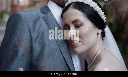 Portrait d'une mariée brune heureuse appuyée sur la poitrine de son mari. Action. Concept de mariage et de départ de la famille. Banque D'Images