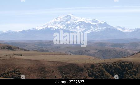 Vallée pittoresque avec prairies jaunes et montagnes froides géantes avec des pics blancs. Créatif. Collines enneigées dans une brume matinale. Banque D'Images