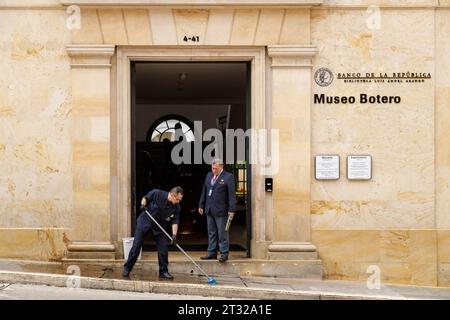 Bogota, Colombie - 2 janvier 2023 : l'homme nettoie le chemin d'entrée du musée Botero pendant qu'un garde de sécurité lui parle Banque D'Images