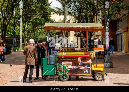 Bogota, Colombie - 2 janvier 2023 : deux hommes discutent autour d'un café à côté d'un chariot de vente dans le parc Santander Banque D'Images