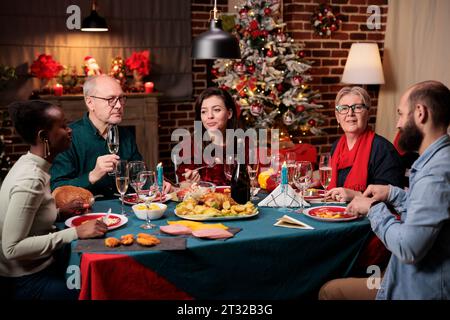 Personne âgée au dîner de fête avec des amis appréciant la célébration de noël à la maison, endroit rempli de décorations et arbre de Noël. Grand-mère préparant la nourriture traditionnelle pour l'événement de la saison des fêtes. Banque D'Images