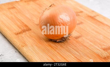 Éplucher et couper l'oignon blanc sur une planche à découper. Recette de soupe de légumes. Gros plan des ingrédients sur la table de cuisine Banque D'Images