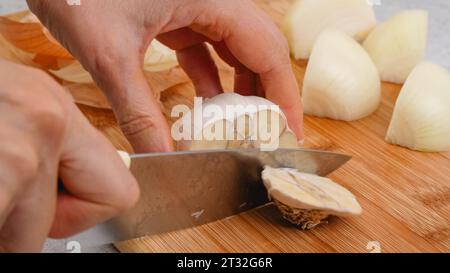 Éplucher et couper l'ail blanc sur une planche à découper. Recette de soupe de légumes. Gros plan des ingrédients sur la table de la cuisine Banque D'Images