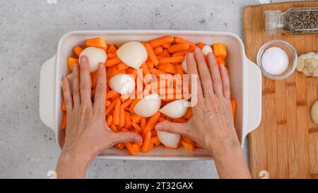 Recette de soupe de courge butternut rôtie. Gros plan des cubes de courge pelés et sans pépins, de la carotte, de l'oignon, de l'ail et des épices dans un plat en céramique sur le kit Banque D'Images