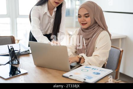 Une femme d'affaires asiatique attrayante et une belle femme d'affaires asiatique-musulmane sont brainstorming et travaillent sur un projet dans la salle de réunion ensemble. Banque D'Images