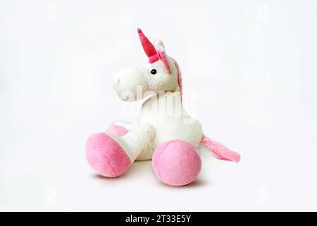 Image d'un jouet licorne souple rose assis sur fond blanc. Image de studio isolée. Photo de haute qualité Banque D'Images