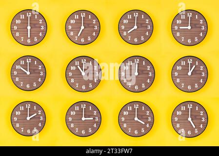 Ensemble d'horloges rondes en bois montrant divers temps 12 heures sur fond jaune. Banque D'Images