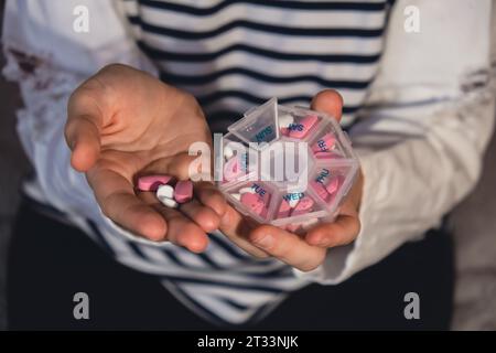 Femme trier les pilules Organiseur des injections hebdomadaires gros plan de la boîte de pilules médicales avec des doses de comprimés pour la journée prendre des médicaments avec des médicaments blancs roses et des capsules. Jeune femme qui reçoit ses vitamines quotidiennes à la maison. Médicaments compléments alimentaires, immunité et prévention des maladies huile de poisson gel Softgel, vitamine D et C minéraux oméga, fibres, acides aminés gras, probiotiques sédatifs. Les soins de santé et les maladies guérissent Banque D'Images