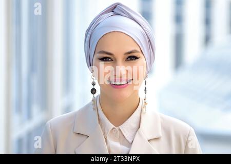 Femme d'affaires musulmane en hijab argenté regarde souriant Banque D'Images