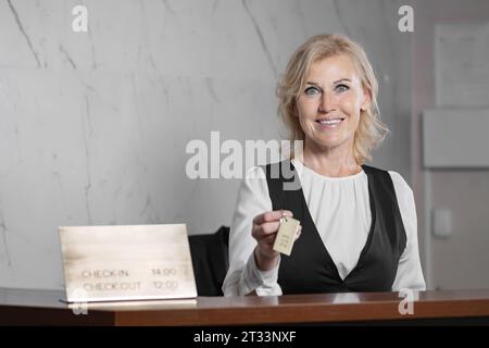 La réceptionniste femme en vêtements formalwear donne la clé au client Banque D'Images