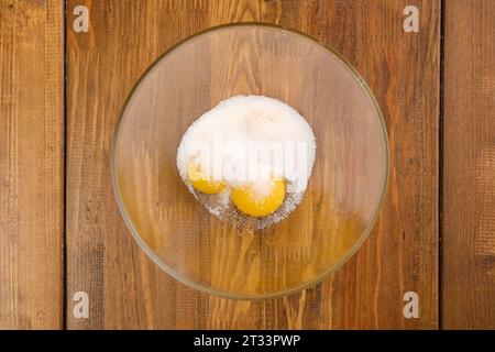 Vue de dessus des œufs et du sucre dans un bol en verre Banque D'Images