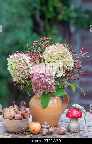 bouquet de fleurs d'hortensia et de hanches roses dans un vase rustique Banque D'Images